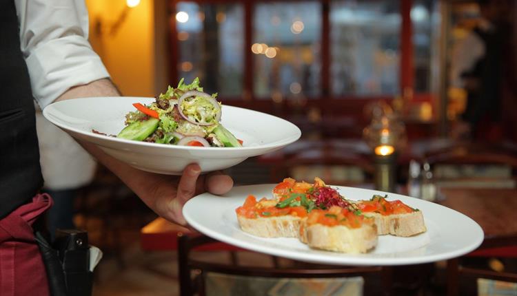 Image of waitstaff holding two dishes at Twelve Eatery